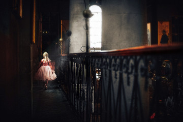 princess in an old castle.little girl with blond hair in a pink dress in a stone house with balconies on the balcony