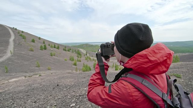 Female tourist taking pictures of nature with camera while hiking in mountains