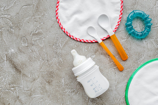 preparation of mixture baby feeding with infant formula powdered milk in bottle, spoon and toys on gray background top view mockup