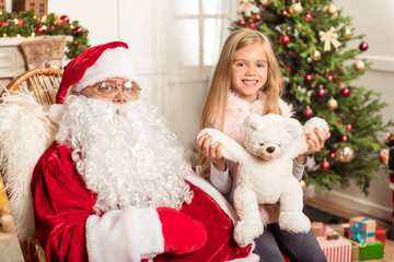 Fototapeta na wymiar Joyful kid celebrating New Year with Santa Claus