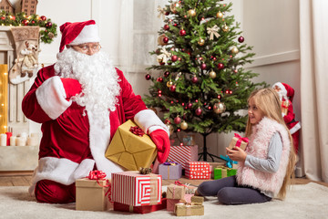 Obraz na płótnie Canvas Cheerful girl receiving Christmas gift from Santa