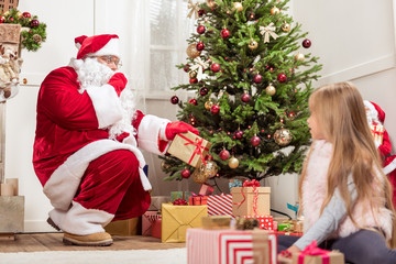 Obraz na płótnie Canvas Secretive Santa putting gifts under tree