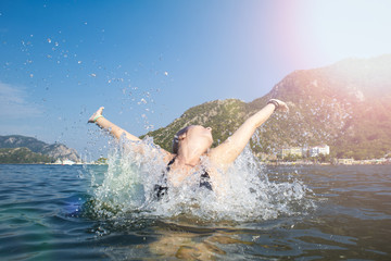 Woman happy jump sea waves splash in tropics on vacation.