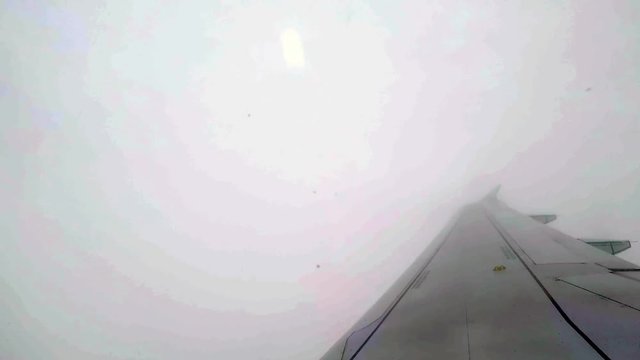 Canted angle shot over wing of airplane as it exits the cloud cover over Montreal, Canada.