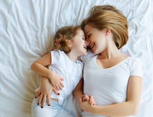  Happy family mother and child daughter laugh in bed