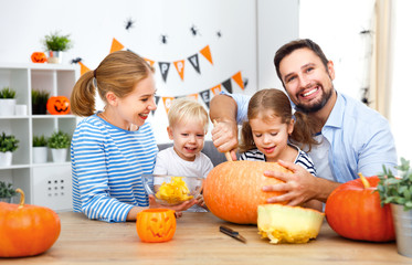 Fototapeta premium happy family mother father and children cut pumpkin for halloween