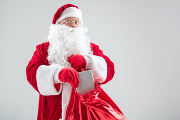 Excited Santa Claus hiding tablet in red sack