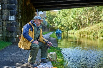 Man Fishing in the Huddersfield Narrow Canal, Marsden, West Yorkshire, England