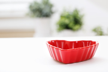 Red heart shaped dish on a white table