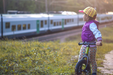 Little girl with bike watching a train