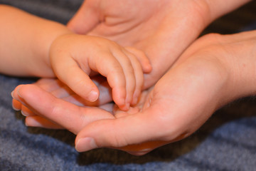 Die Hand eines Babys liegt in den Händen der Mutter