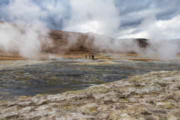 Iceland landscape. Steaming geothermal sources. People walking around and watching geologic features.
