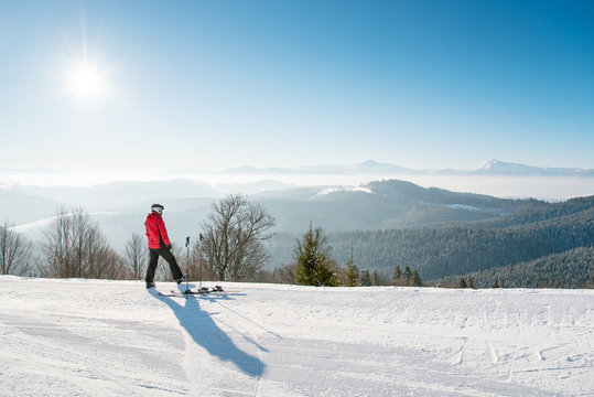 Rearview shot of a man skier resting after the ride standing on top of the ski slope looking around enjoying breathtaking view of snowy mountains on a sunny winter day seasonal recreational extreme