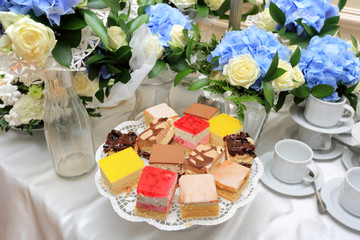 Stół szwedzki z ciastem i kwiatami na przyjęciu weselnym w restauracji, katering.