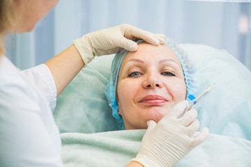 Obraz na płótnie Canvas Cosmetologist beautician making injection to senior woman