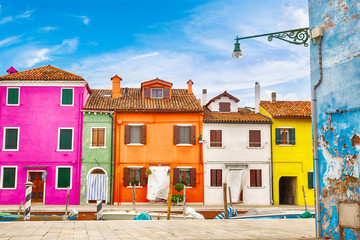 Fototapeta na wymiar Colorful houses in Burano island with cloudy blue sky near Venice, Italy. Popular and famous tourist place