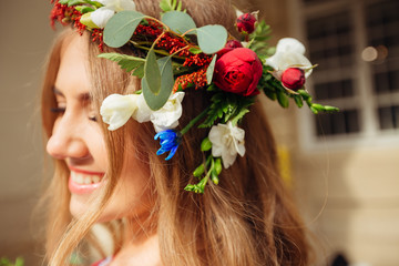 Naklejka premium Creative crown of fresh flowers on a head of beautiful blond girl