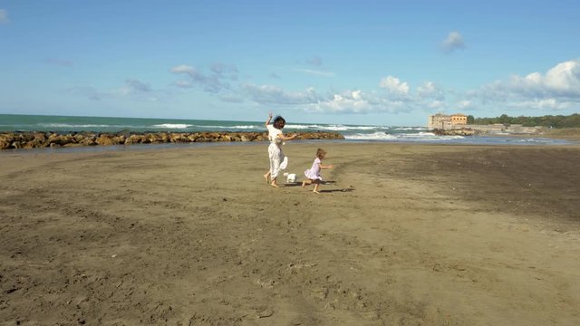 Beautiful woman with little daughter and dog dancing on beach feeling happiness love and freedom 4K slow motion