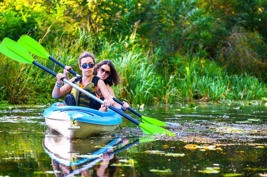 Family kayaking, mother and child paddling in kayak on river canoe tour, active summer weekend and vacation, sport and fitness concept
