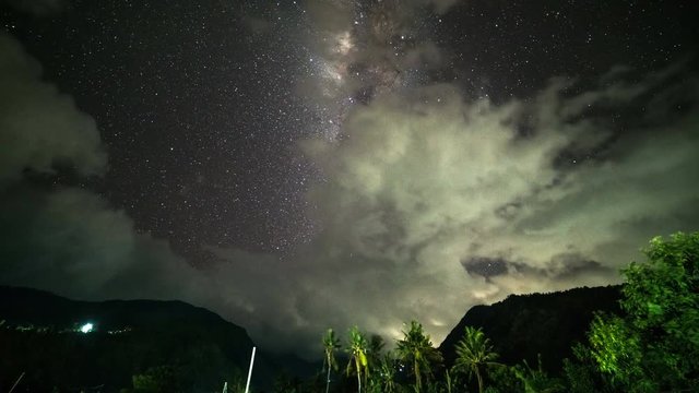 Night landscape timelapse with colorful Milky Way and cloudy light at mountains. Starry sky with tropical mountains on the island of Bali in Indonesia.