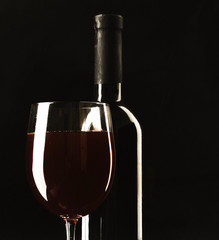 Glass of wine and a bottle on black background