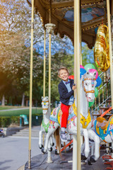 Fototapeta na wymiar Boy with bunch of colorful balloons on the carousel in Paris.
