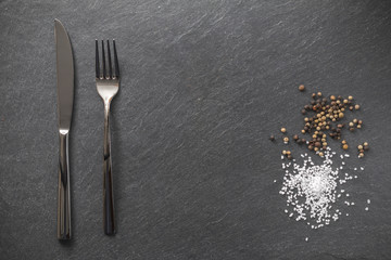 Besteck mit Salz und Pfeffer auf Schieferplatte