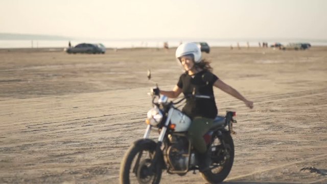  beautiful young woman motorcyclist rides an old cafe racer motorcycle and dances on it 