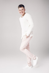 handsome young man in a white sweater and pants 