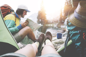 Young couple camping together in stunning mountain wilderness near the lake. POV from the tent....