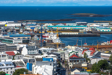 Fototapeta na wymiar Beautiful super wide-angle aerial view of Reykjavik, Iceland with harbor and skyline mountains and scenery beyond the city, seen from the observation tower of hallgrimskirja