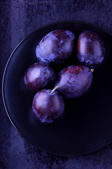 Obraz premium Plums on a black plate for designer