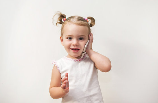 Little girl speaking by cell phone, white background