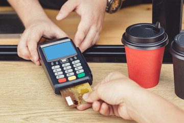 PErson paying bill with credit card for coffee to go
