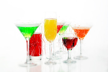Seven cocktail and wine glasses with color drinks   on the reflecting surface.