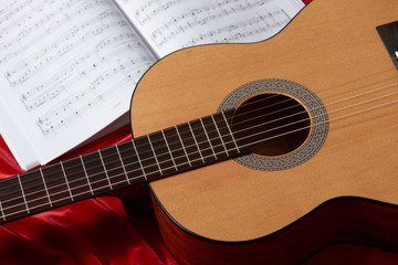 Plakat acoustic guitar and music notes on red fabric, close view of objects