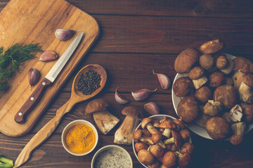 Fresh mushrooms with spices and herbs on a wooden board as ingredients