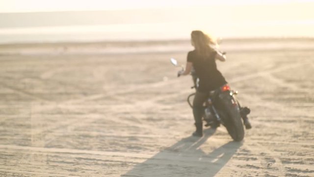  beautiful young woman riding an old cafe racer motorcycle on desert at sunset or sunrise. Female biker 