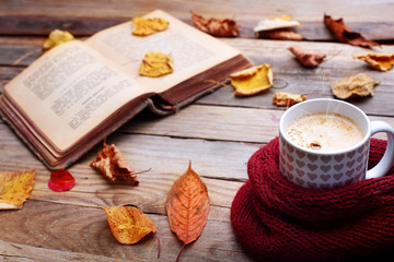 Fototapeta na wymiar Cup hot cappuccino coffee on wooden table with autumn leaves ,book.Autumn concept.Warm autumn picture .Selective focus.Copy space