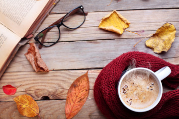 Fototapeta na wymiar Cup hot cappuccino coffee on wooden table with autumn leaves ,book and eyeglasses.Autumn concept.Warm autumn picture .Selective focus.Top view