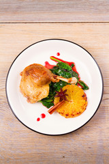 Duck leg with spinach, orange and spices: cinnamon and star anise in red wine sauce. Verical view from above, top shot