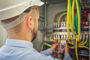 Engineer electric measures multimeter voltage of high-power electrical circuits.