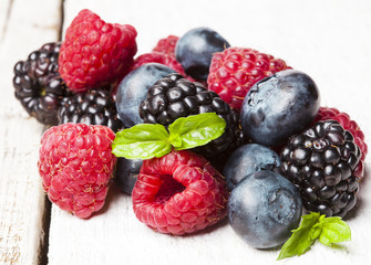 Ripe and sweet berries on white wooden background