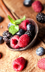 Ripe and sweet berries in a spoon on wooden background