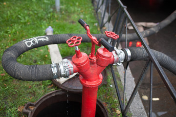 Fire hose hooked up to a rusty red fire hydrant