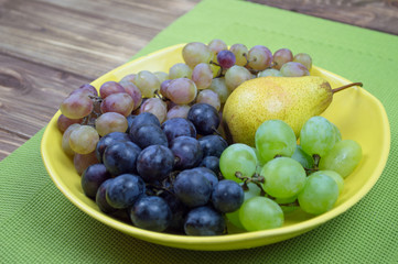 Fresh rose and green grapes and pear. Grapes on a yellow plate
