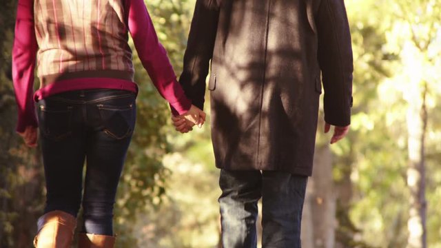 Couples holding hands down autumn lane