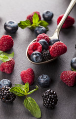 Ripe and sweet berries in vintage metal spoon on black background