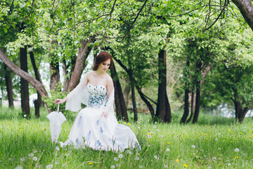 Woman in long white dress in summer garden