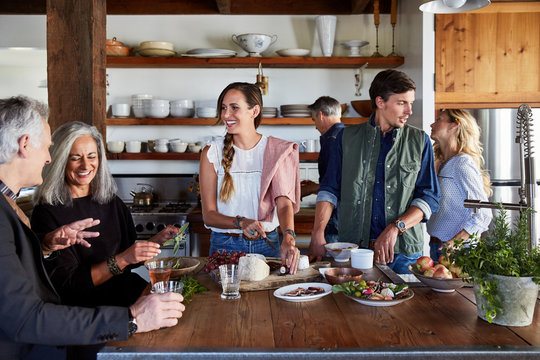 Family And Friends Cooking Together In Rustic Farmhouse Kitchen